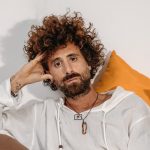 Foto di Gio Evan seduto su un divano con cuscini colorati