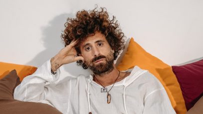 Foto di Gio Evan seduto su un divano con cuscini colorati