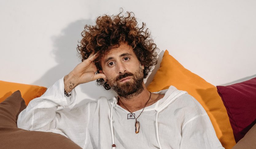 Foto di Gio Evan seduto su un divano con cuscini colorati