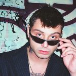 Tommy Dali davanti a un muro con graffiti