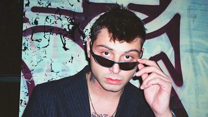 Tommy Dali davanti a un muro con graffiti