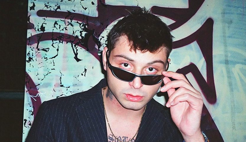 Tommy Dali davanti a un muro con graffiti