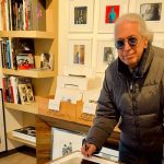 Guido Harari con delle stampe alle spalle