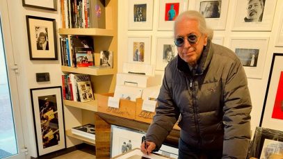 Guido Harari con delle stampe alle spalle