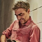 Marco Ligabue contro un muro con una chitarra