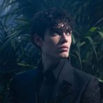 Biondo in un giardino con una rosa nera