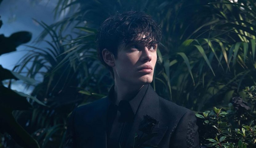 Biondo in un giardino con una rosa nera