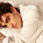 Michele Bravi su un letto bianco