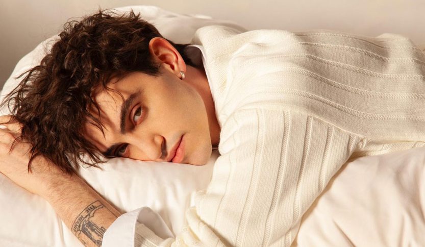 Michele Bravi su un letto bianco