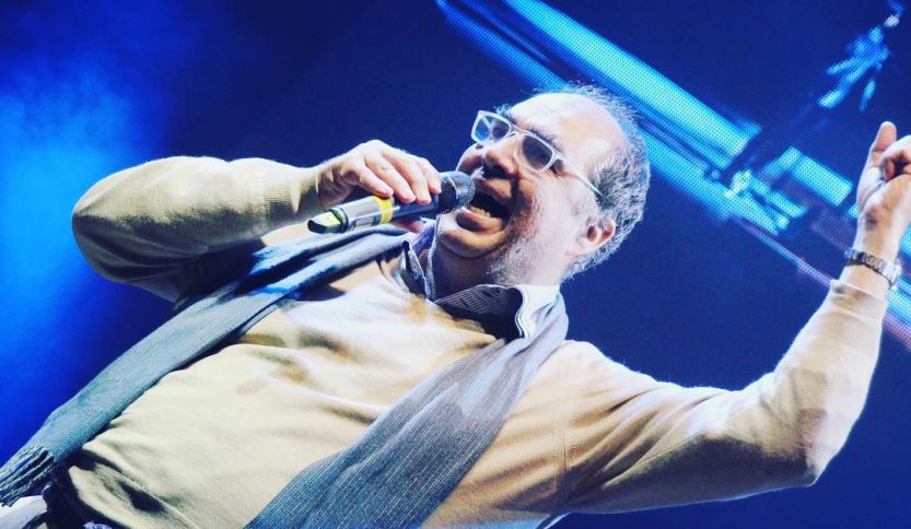 Pietro Ubaldi con sfondo blu e microfono