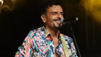 Davide de Marinis con microfono su sfondo nero con fumo giallo