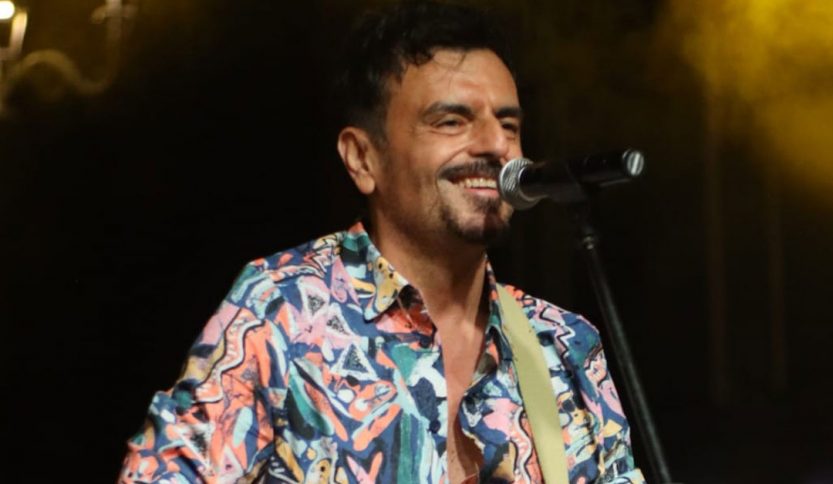 Davide de Marinis con microfono su sfondo nero con fumo giallo