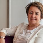 Foto di Lucia Fracassi con sfondo bianco e poltrona e tenda viola