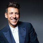 Francesco Gabbani sorride con sfrondo scuro
