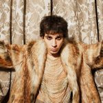 Alex Wyse con tenda oro dietro