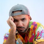 Alex Polidori con cappello e sfondo azzurro