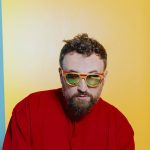 Dargen D'Amico in rosso con sfondo giallo e celeste