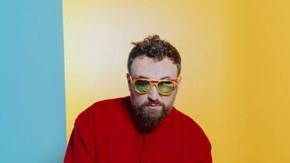 Dargen D'Amico in rosso con sfondo giallo e celeste