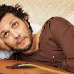 Ermal Meta sdraiato con chitarra