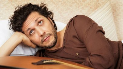 Ermal Meta sdraiato con chitarra