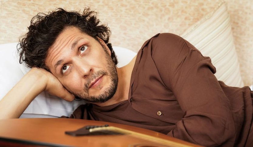 Ermal Meta sdraiato con chitarra