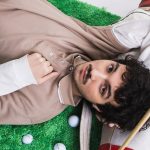 Mazzariello sdraiato su un prato con delle mazze da golf