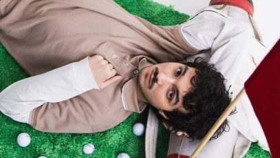 Mazzariello sdraiato su un prato con delle mazze da golf