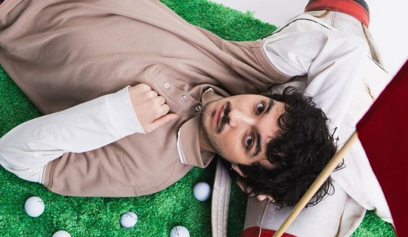 Mazzariello sdraiato su un prato con delle mazze da golf