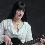Roshelle con sfondo nero e chitarra